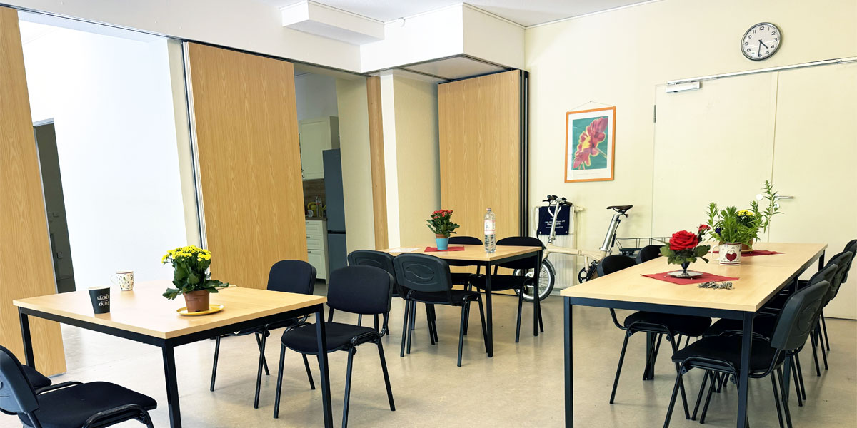 Heller Aufenthaltsraum der Tagespflege in Berlin mit Blumen auf den Tischen und freundlicher Atmosphäre