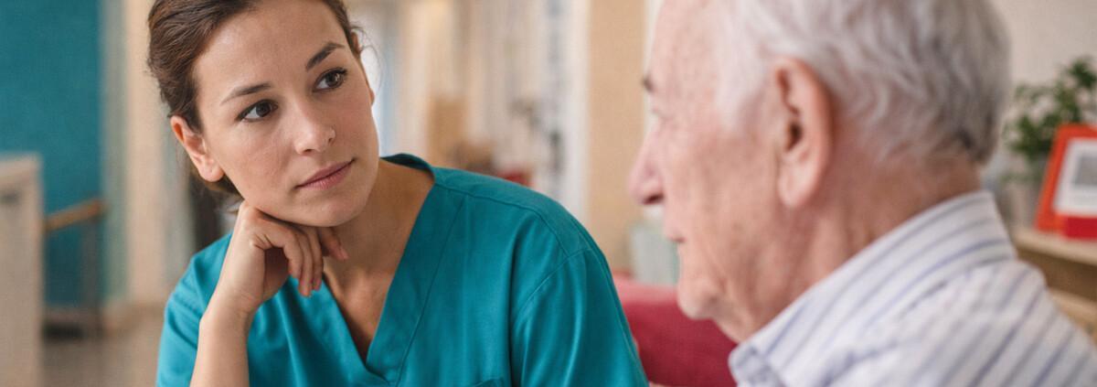 Pflegekraft beobachtet aufmerksam einen älteren Bewohner zur Früherkennung von Suchtkranken in der Altenpflege